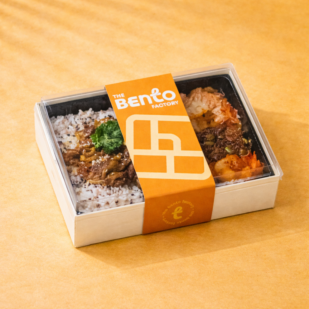 Korean style gochu bento and 'The Bento Factory' packaging on a yellow background