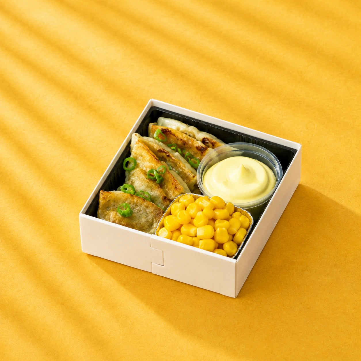 Crispy spring onion pancake with corn and dipping sauce on a yellow background