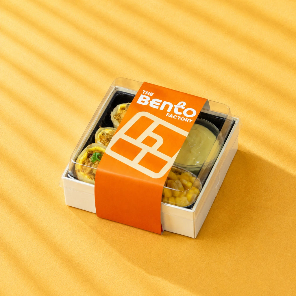 Bento box with food items from The Bento Factory on a yellow background